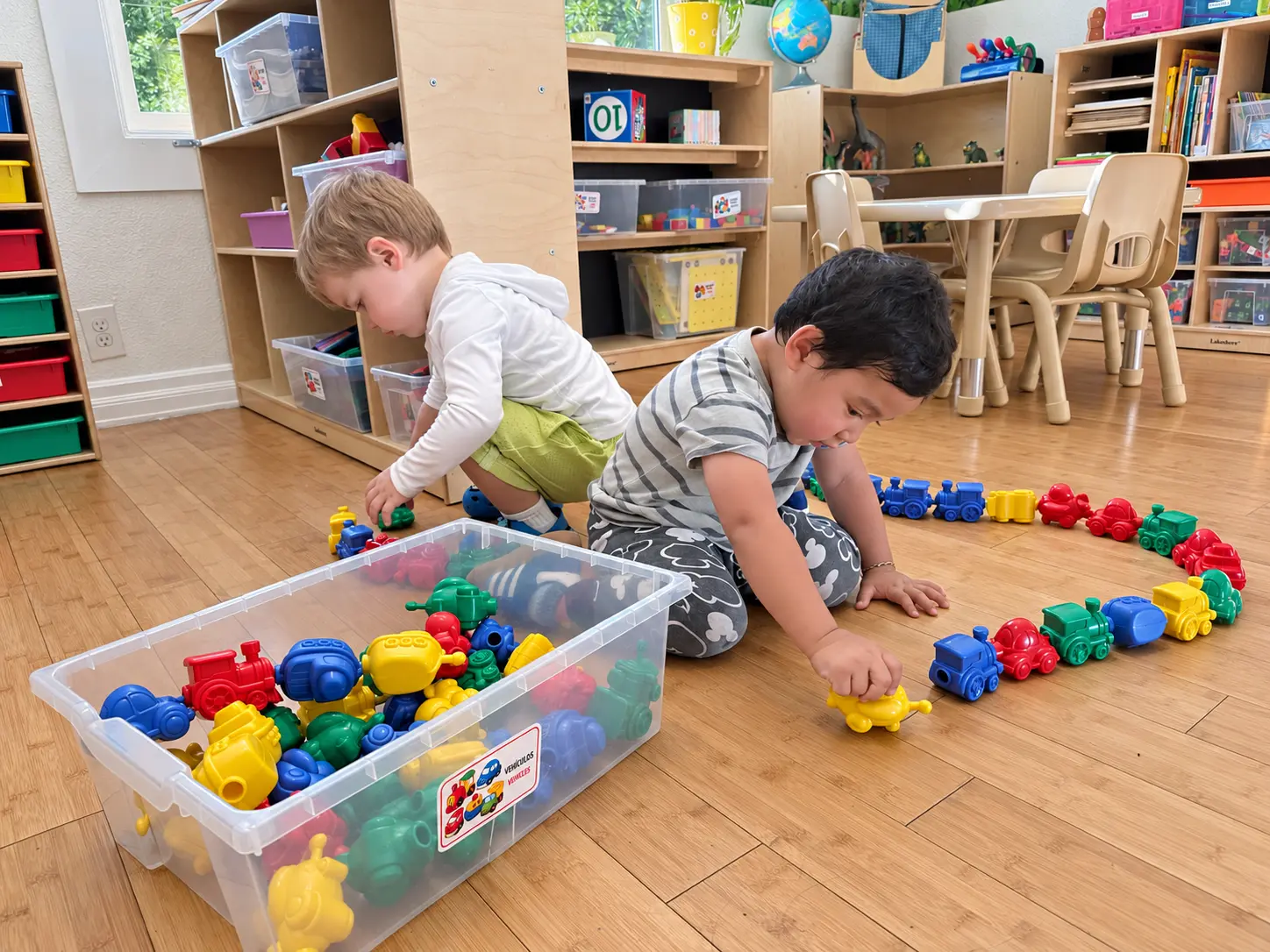 Two young niños aprendiendo through play with colorful toy trains